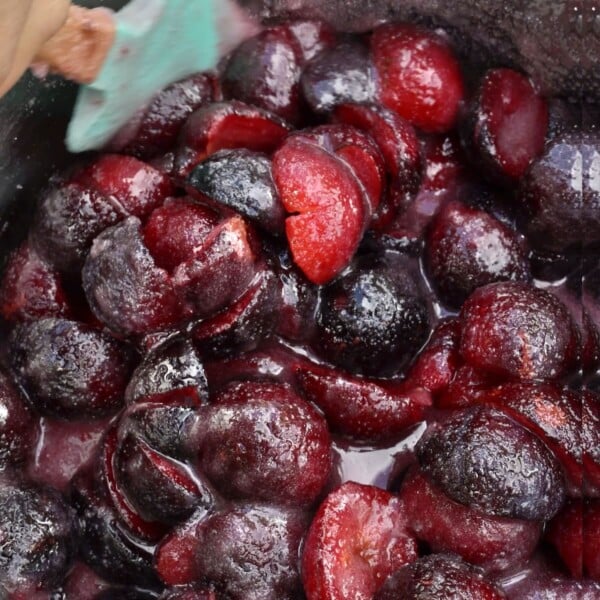 Plums and sugar mixed in a large saucepan.