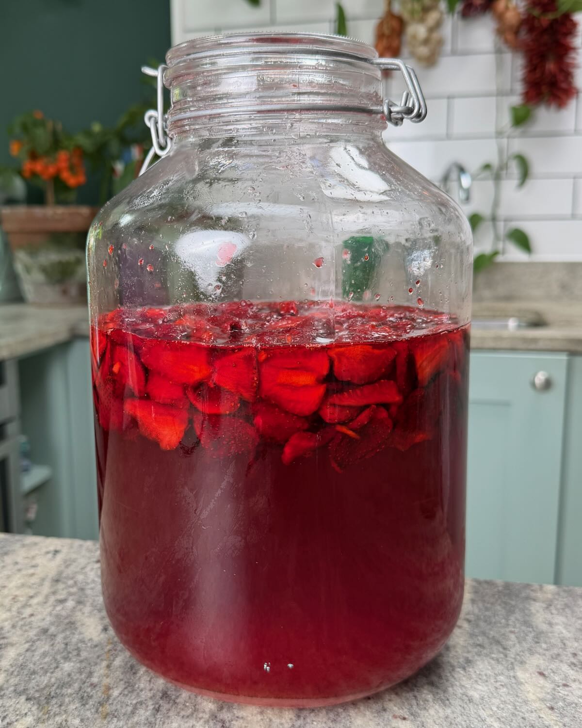 A large jar with homemade strawberry cheong syrup.