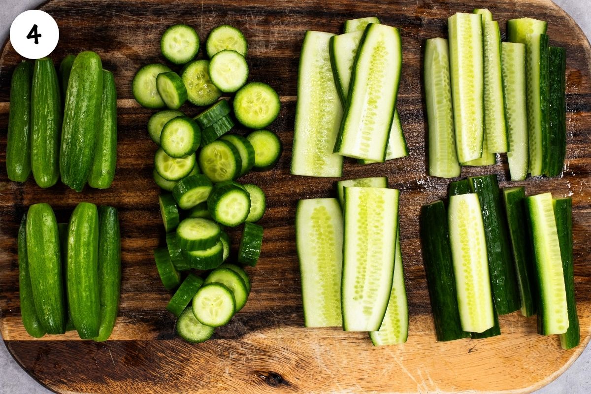 Cucumbers prepared three ways on a wooden board, showing whole cucumbers, sliced rounds, halved spears, and quartered spears for pickling.
