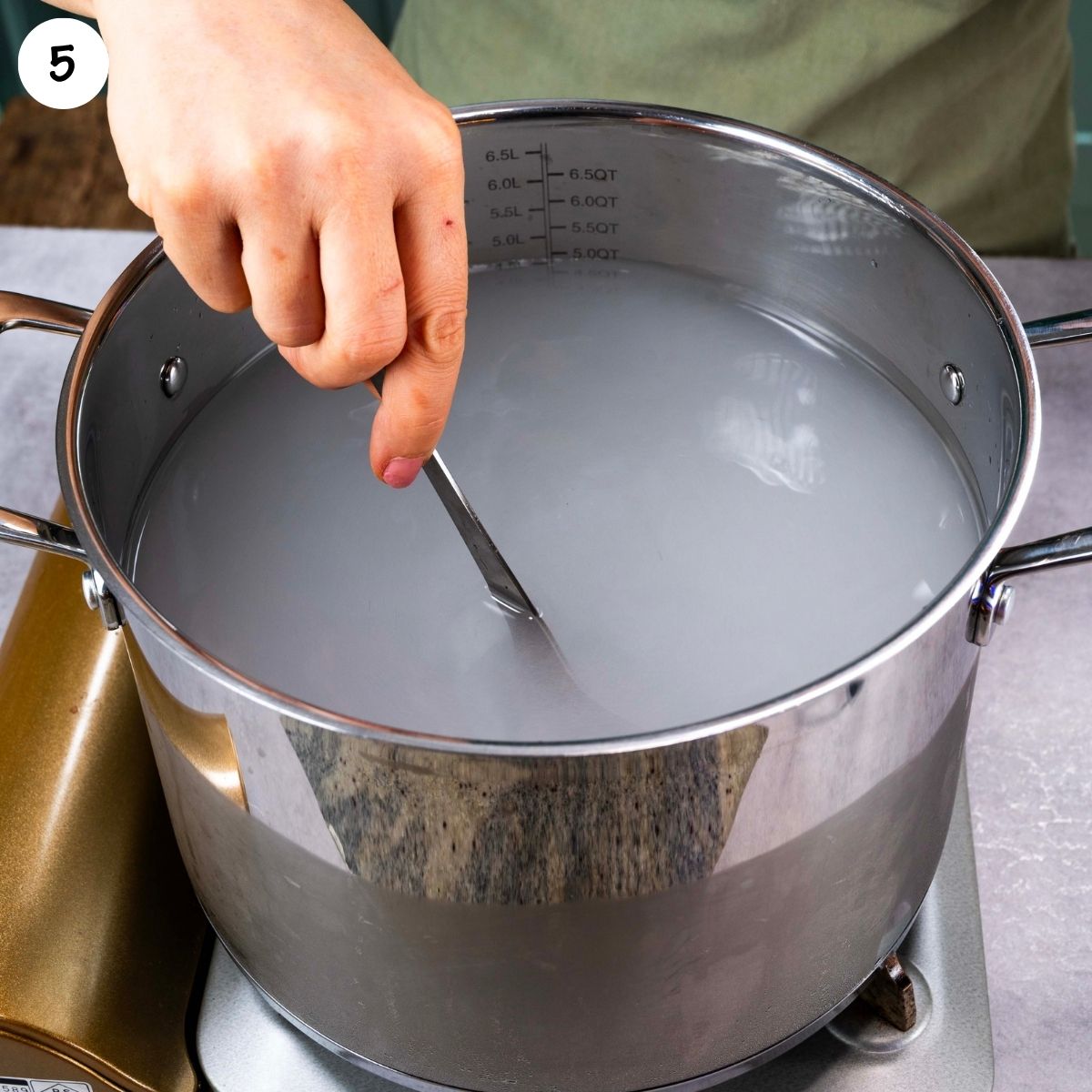 Brine ingredients being stirred in a large pot with vinegar, water, pickling salt, and sugar until dissolved.