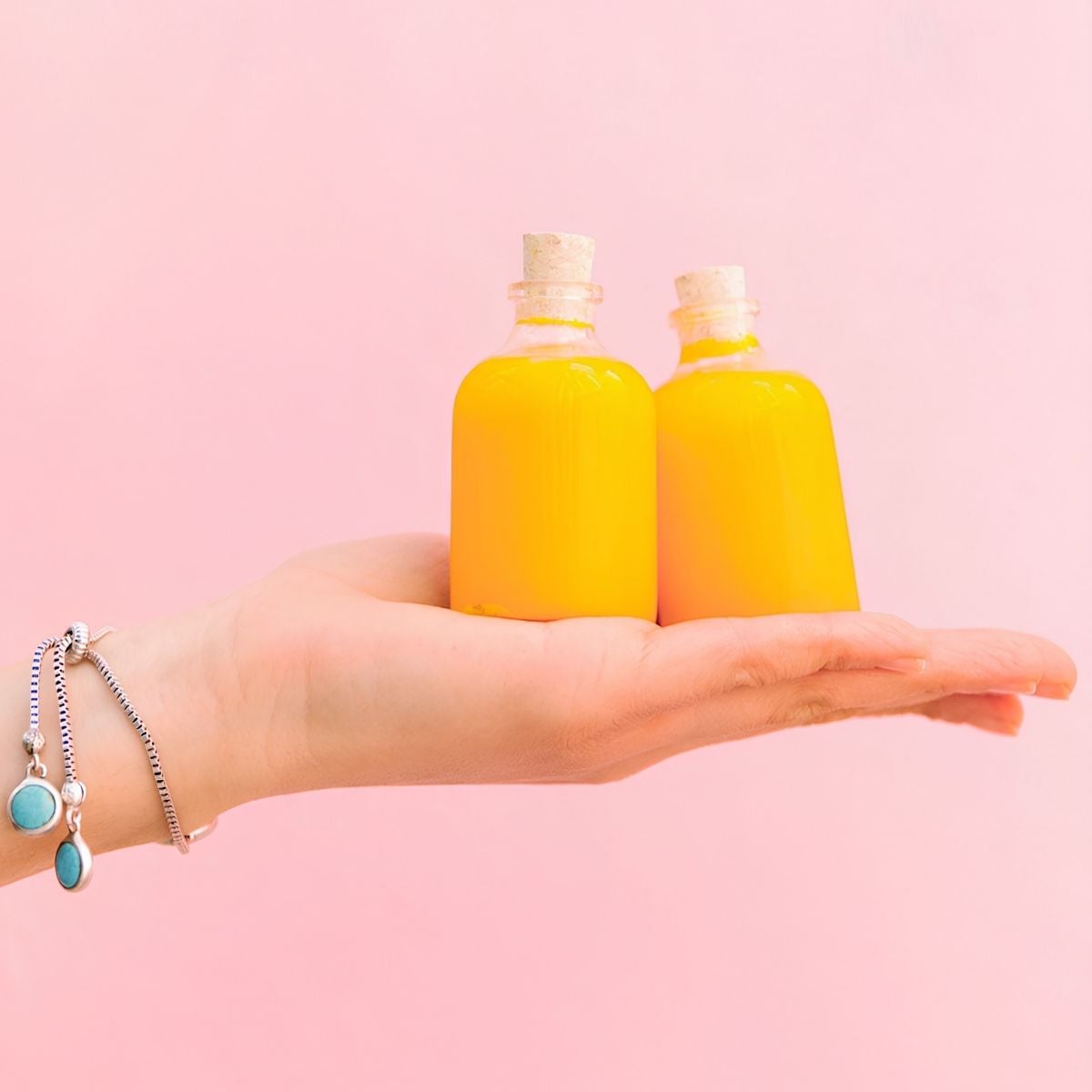 A hand holding two small bottles with homemade energy shots.