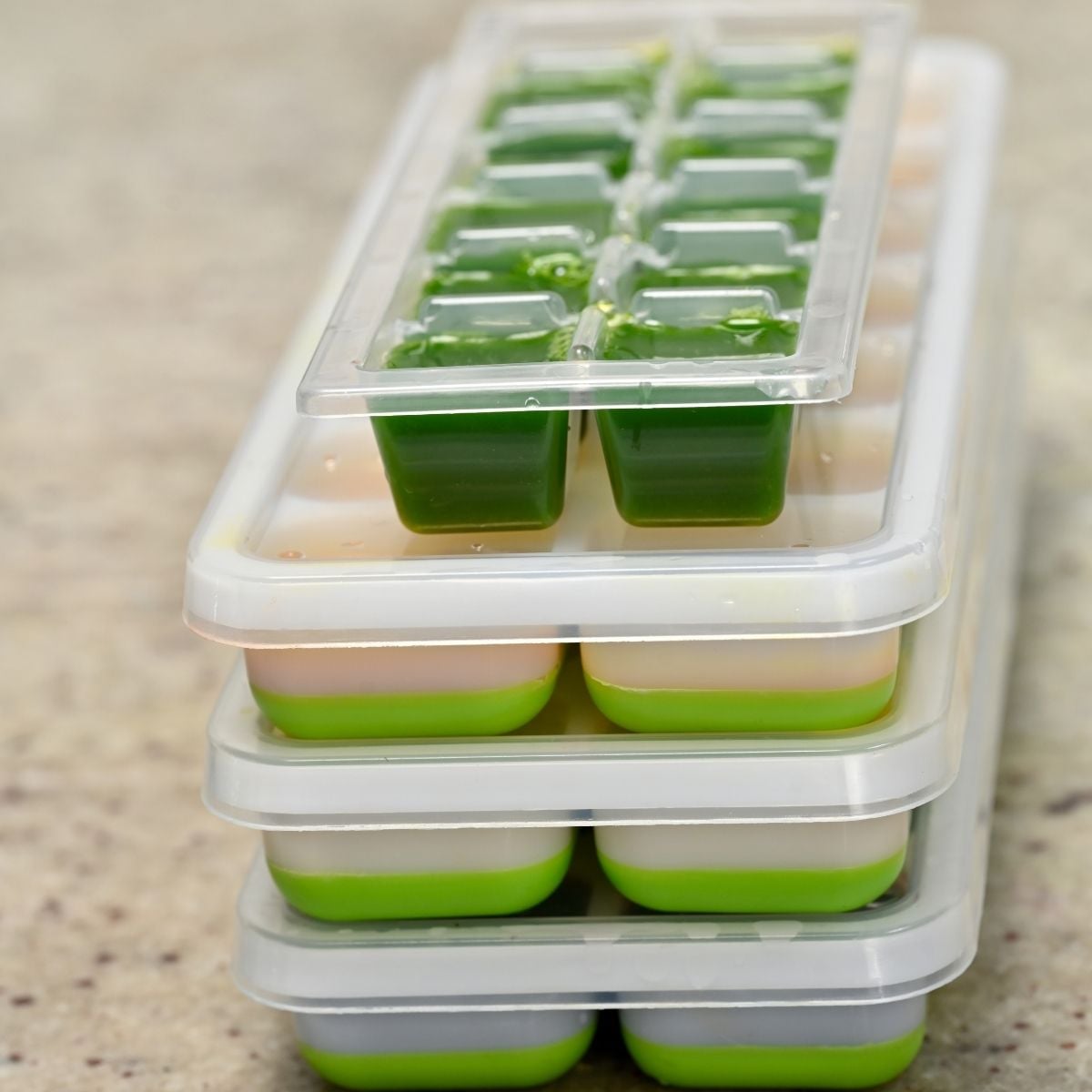 A stack of covered ice cube trays filled with wellness shots for long-term preservation..