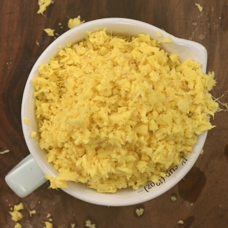 A cup packed with grated fresh ginger.