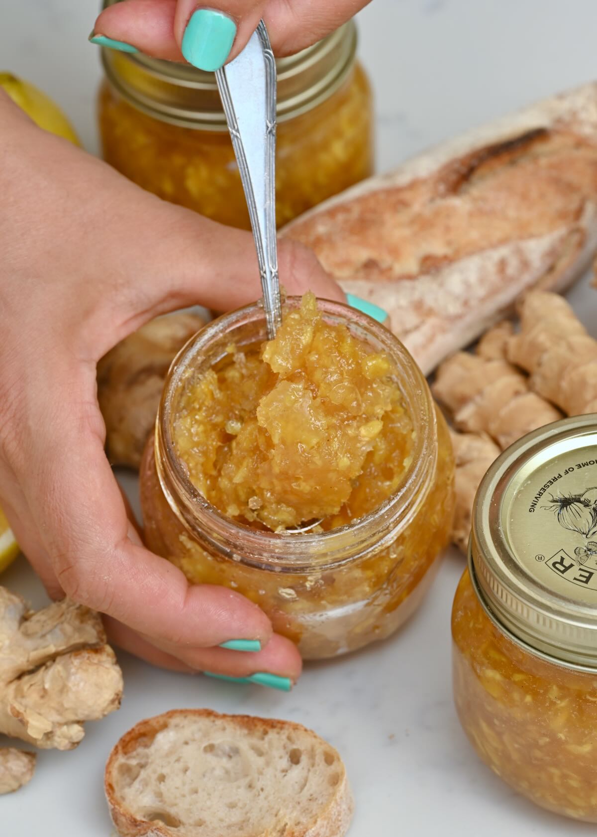 A small jar with homemade ginger jam and a spoon dipped inside.