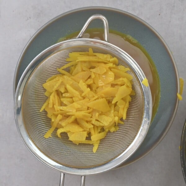 Softened lemon peel in a colander with discarded water.