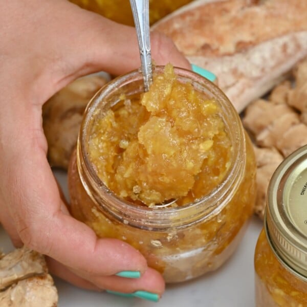 A small jar with homemade ginger jam and a spoon dipped inside.