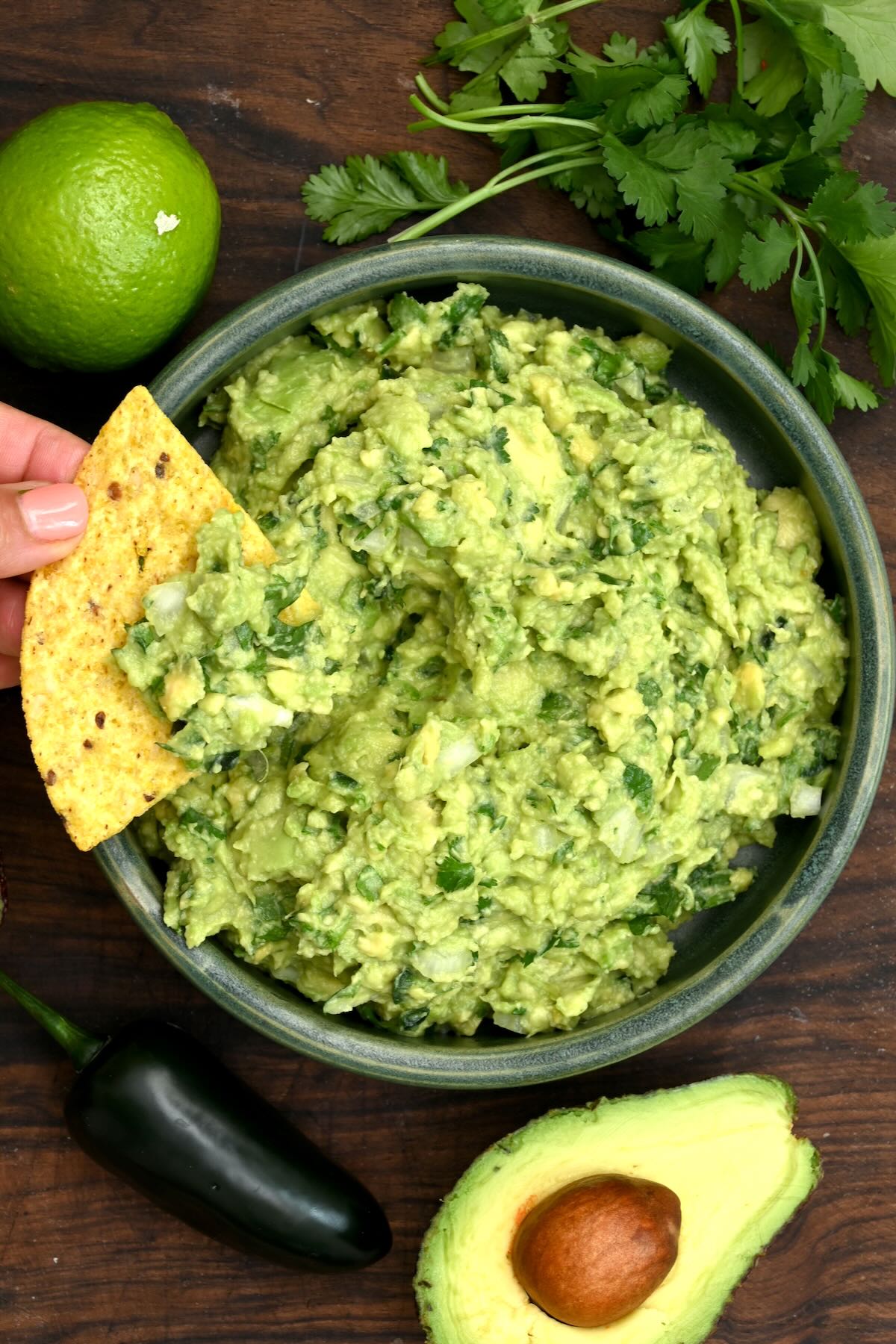 Guacamole in a small bowl with a tortilla chip dipping into it.