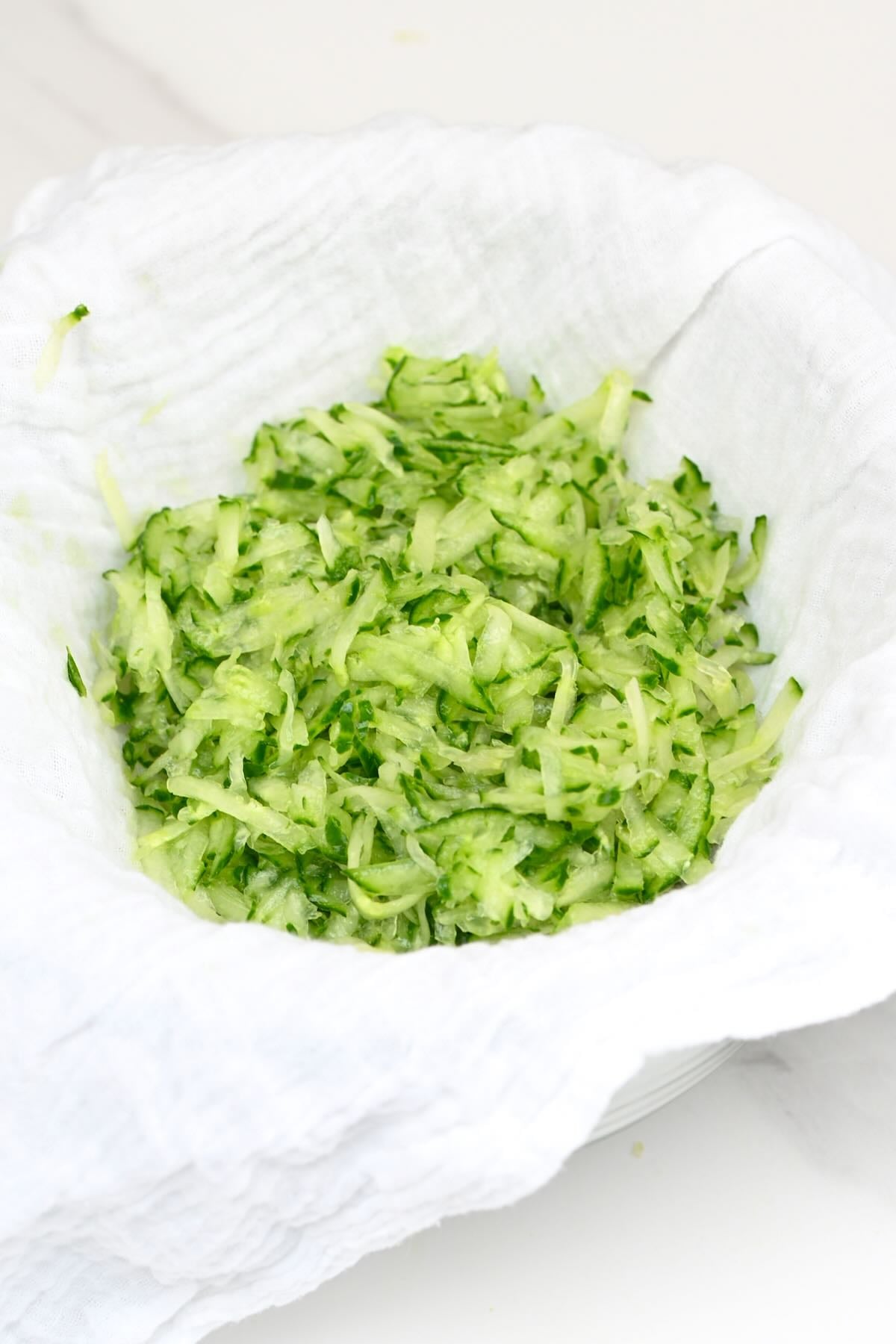 Freshly grated cucumber resting inside a white cheesecloth for draining liquid.