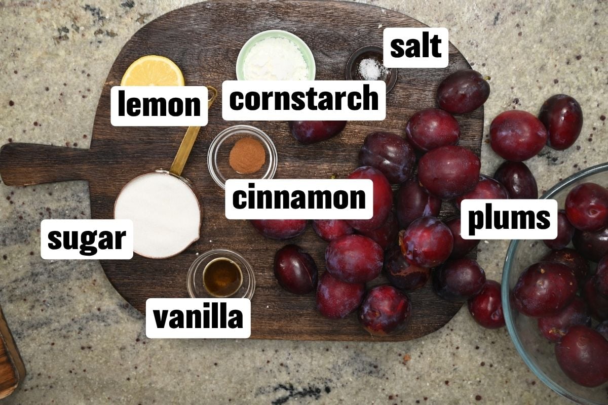 Ingredients flat-lay for plum crisp filling, including fresh plums, sugar, lemon, and spices.
