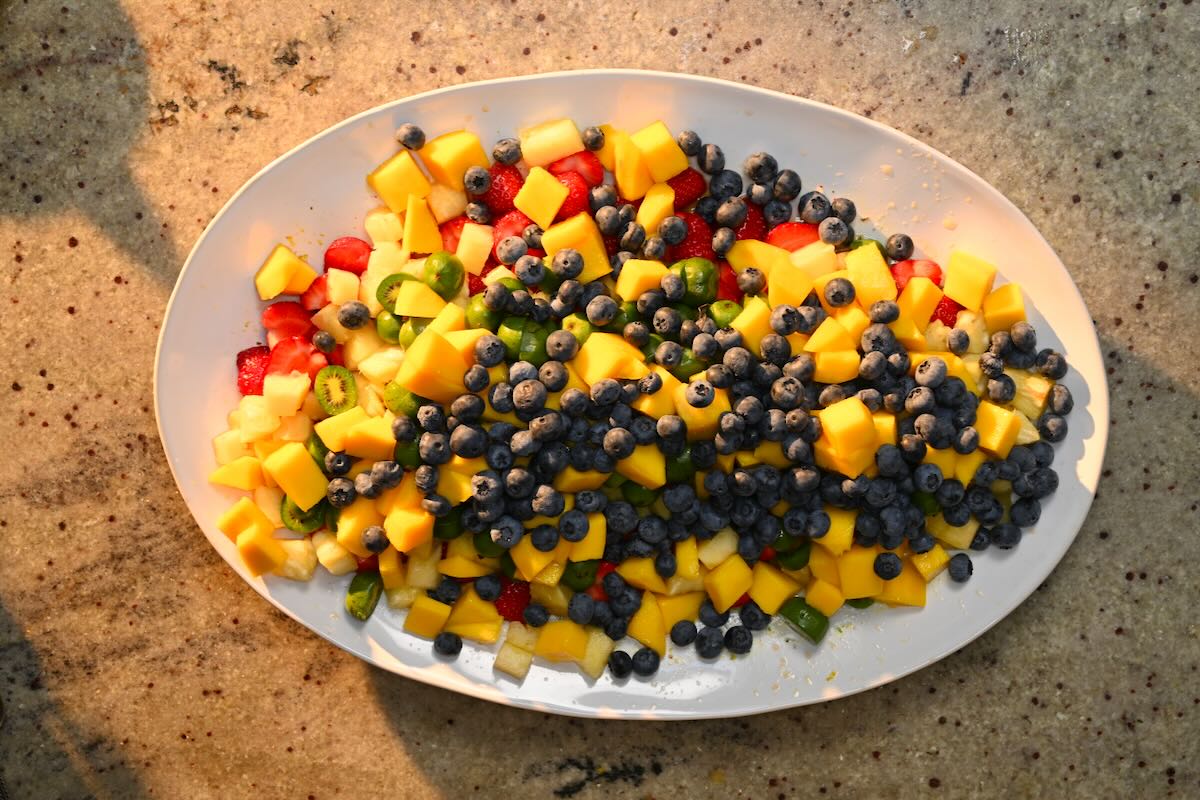 Fruit salad ingredients mixed in a large plate.