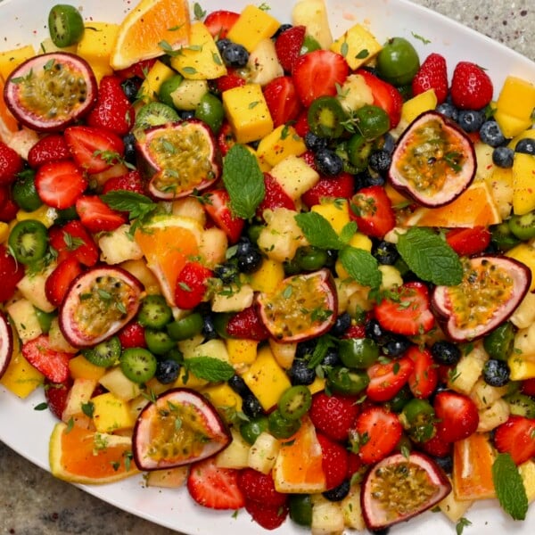 A large serving dish with freshly made fruit salad topped with passion fruit and orange slices.
